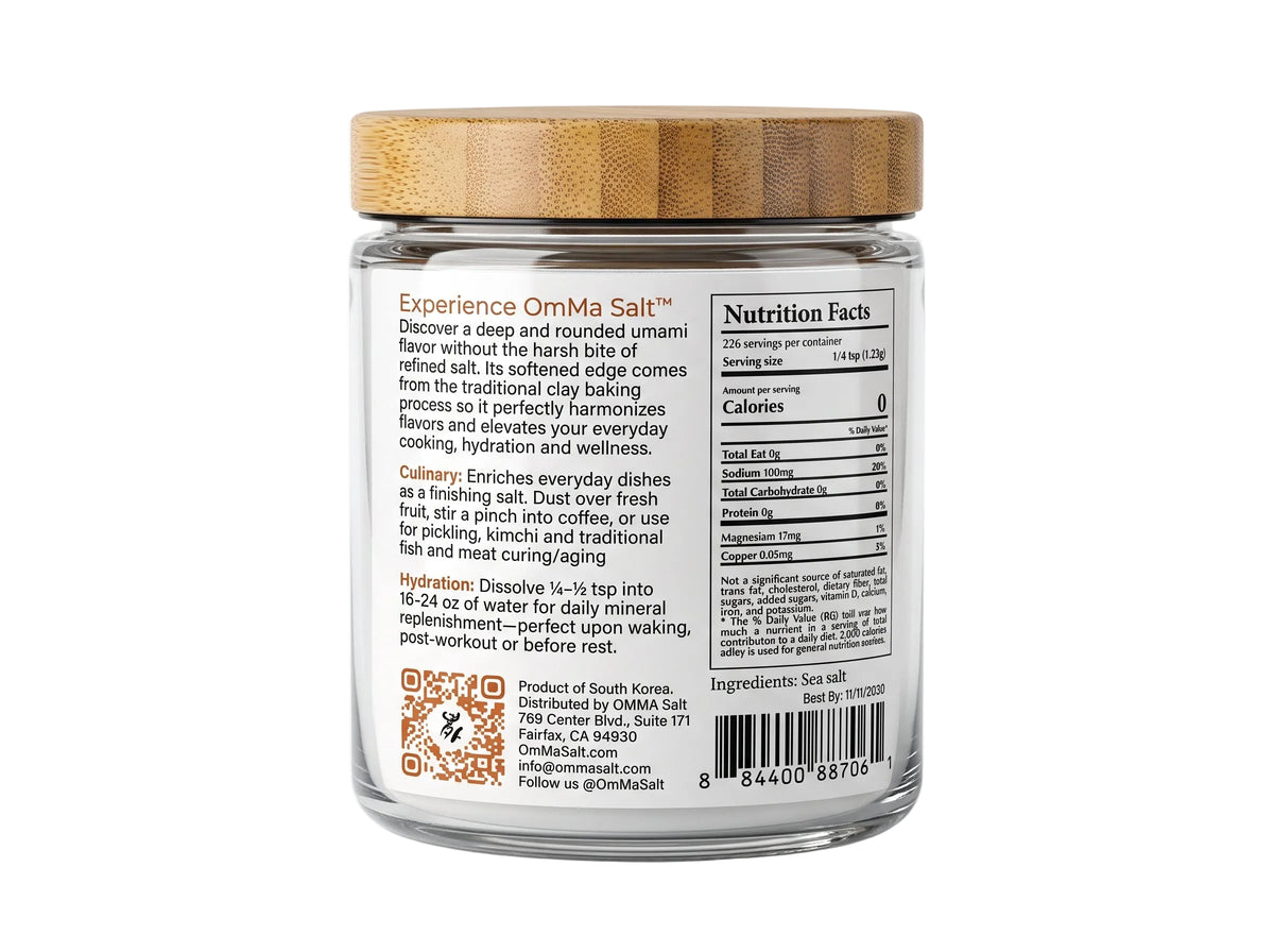 A jar of OmMa Clay-Baked Salt on a plain white background. The product is in a clear glass jar with a light brown bamboo-style lid and a white label featuring the brand name 'OmMa' and an illustration of a clay pot containing white salt.

OmMa salt. clay-baked mineral rich sea salt from South Korea. Corse mineral rich sea salt in 8 oz glass jar premium artisan salt no chemicals or machinery 6 times more minerals than table salt low sodium hand-harvested, hand-raked. 